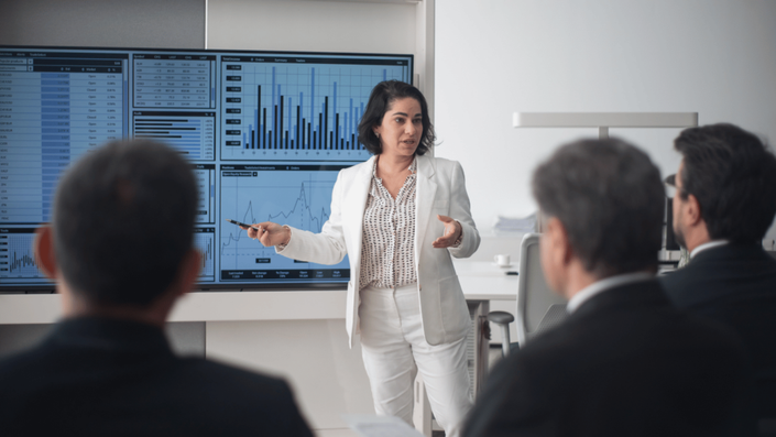 Profesional dando una presentación sobre Invertir en la Bolsa Mexicana, mostrando gráficos financieros y análisis de datos en una pantalla.