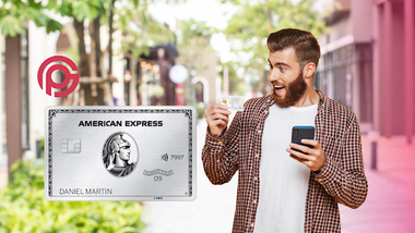 un hombre usando su teléfono celular mientras mira una tarjeta Platinum American Express