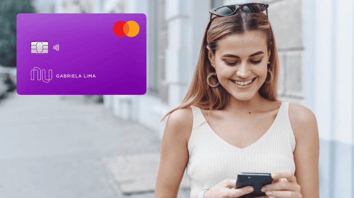 mujer sonriendo en el teléfono celular con tarjeta de crédito nubank